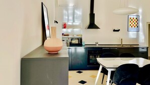 A modern kitchen with a dining area, a large pendant light, and a microwave. - GuestHost - The Design Pasta Apartment (Roma)