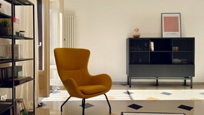 A modern living room with a yellow armchair, a black bookshelf, and a framed picture on the wall. - GuestHost - The Design Pasta Apartment (Roma)
