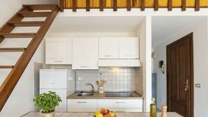 A kitchen with white cabinets, a wooden countertop, a sink, and a staircase. - Gariboldi by Interhome (Palau)
