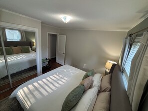 Une chambre avec deux lits, une table de chevet avec une lampe et une porte donnant sur une autre pièce.