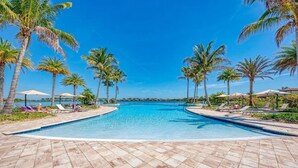 A pool area with tiled flooring, lounge chairs, and palm trees. - Lake Front View, 6 miles from beaches (Nokomis)