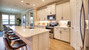 A modern kitchen with white cabinets, stainless steel appliances, and a central island with bar stools. - Lake Front View, 6 miles from beaches (Nokomis)