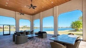 A covered outdoor patio with wicker furniture, a table, and ceiling fans. - Lake Front View, 6 miles from beaches (Nokomis)