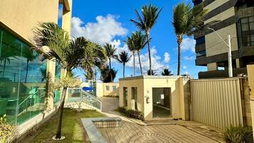 A courtyard with palm trees, a small seating area, and a building with large windows.