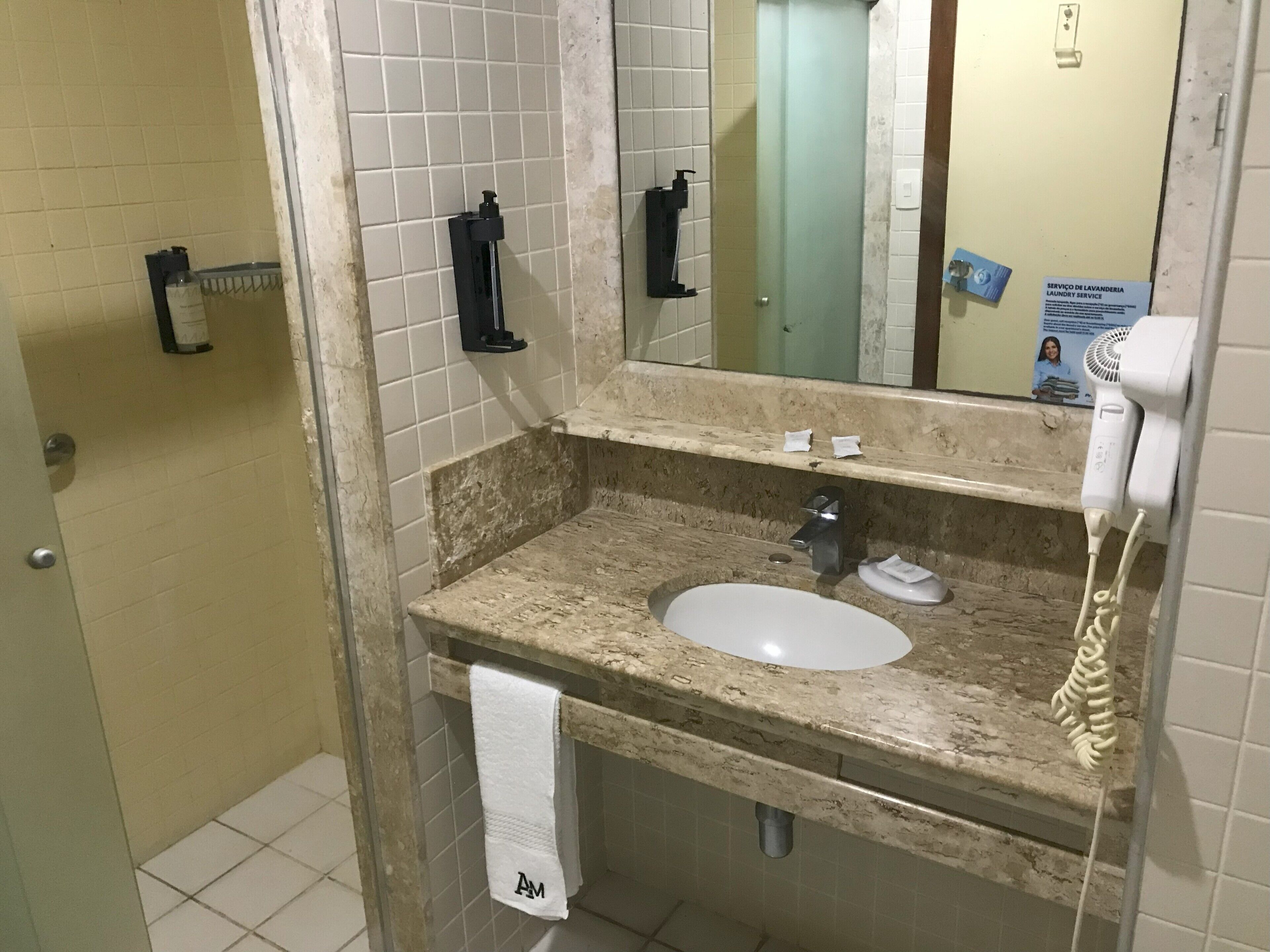 Casa de banho com lavatório, espelho, porta-toalhas e secador de cabelo.