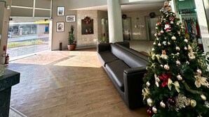 A spacious lobby with a large Christmas tree, a double-height ceiling, and a view of the street outside.