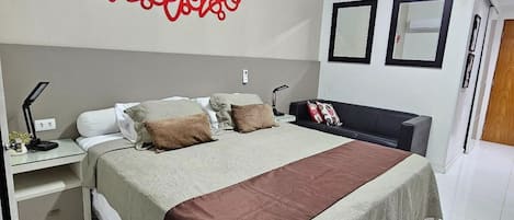 A modern bedroom with a large bed, bedside tables, a wall-mounted air conditioner, and a ceiling light.