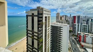 Ein Hochhaus mit mehreren Balkonen mit Blick auf Strand und Meer.