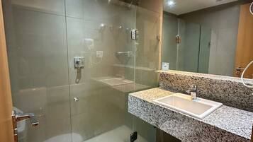 Un baño moderno con ducha de vidrio, lavamanos de encimera de granito y un inodoro.