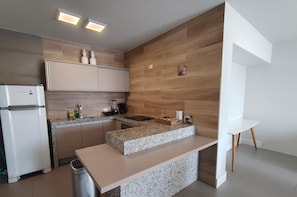 A modern kitchen with a built-in island, wooden wall paneling, and a white countertop.