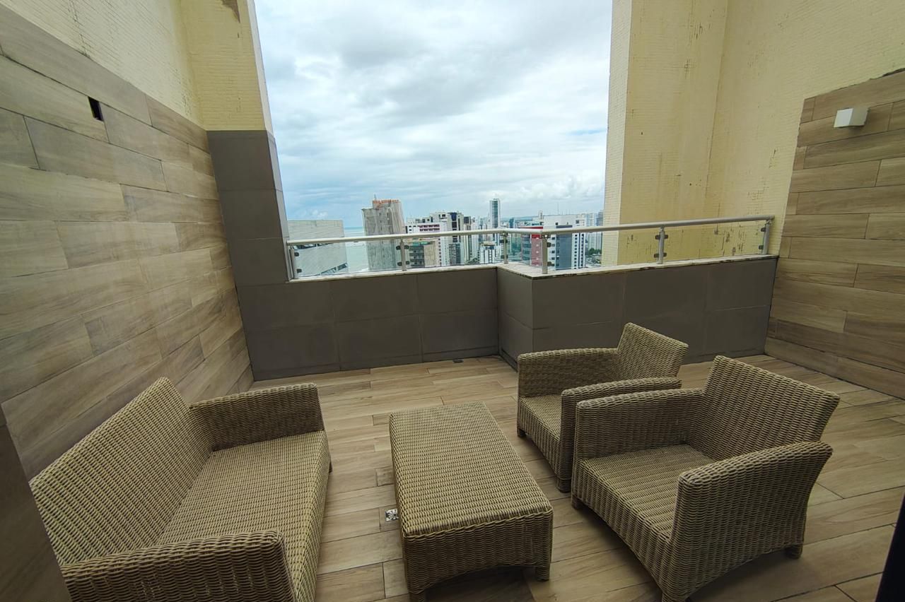 A balcony with wicker furniture, a view of the city, and a railing.