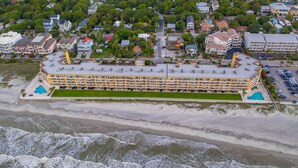Luchtbeeld van een kusthotel met meerdere balkons, een zwembad en een strandgedeelte.