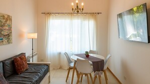 A dining area with a table, chairs, a chandelier, a sofa, a radiator, and a painting on the wall. - Luna Azul. Condo. Fast Wifi. Free Parking. (San Carlos de Bariloche)