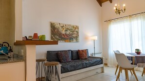 A living room with a sofa, a coffee table, a dining table with chairs, a chandelier, and a painting on the wall. - Luna Azul. Condo. Fast Wifi. Free Parking. (San Carlos de Bariloche)