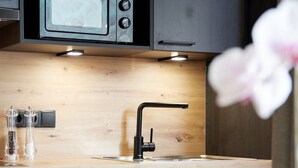 Una cocina moderna con encimera de madera, grifo negro y un microondas sobre el fregadero.