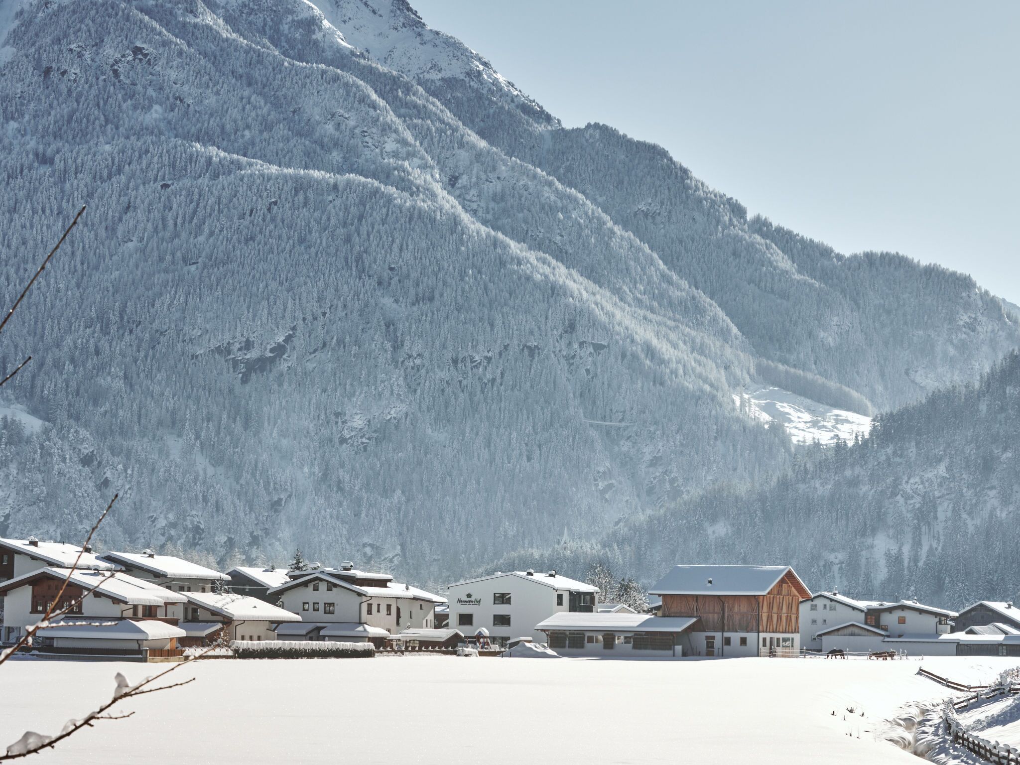 Un village de montagne enneigé, avec des bâtiments traditionnels en bois et une vue dégagée sur les sommets environnants.