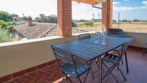 Un patio cubierto con mesa y sillas, una chimenea de ladrillo y vistas del paisaje circundante.