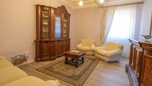 Una sala de estar con un mueble de madera, dos sillones, un sofá y una mesita de centro.