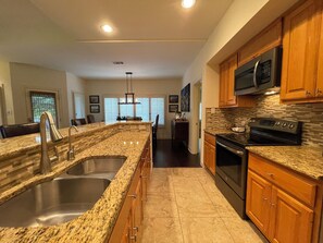 A modern kitchen with granite countertops, stainless steel appliances, and wooden cabinets. - Hill Country getaway at Barton Creek Lakeside near Lakecliff Golf Club. (Spicewood)