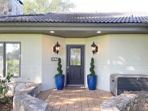 A house entrance with a dark door, two wall-mounted lanterns, a mailbox, and two large blue planters. - Hill Country getaway at Barton Creek Lakeside near Lakecliff Golf Club. (Spicewood)