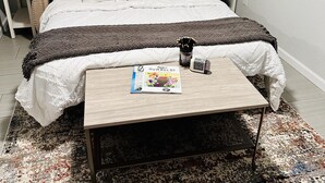 A neatly arranged bedroom with a bed, bedside tables, a coffee table, and a rug. - New, Fun-Size Benbow House! (Garberville)