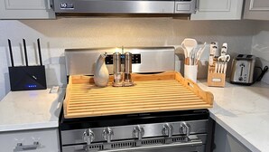 A kitchen with a stainless steel range hood, a microwave, a toaster, and a wooden cutting board. - New, Fun-Size Benbow House! (Garberville)