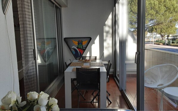 Een balkon met een tafel en stoelen, een decoratief object aan de muur en uitzicht op de omgeving.