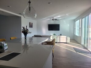 A modern living room with a large island table, a sofa, and a TV.