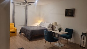 A compact bedroom with a bed, a desk, two chairs, a ceiling fan, and a window with blinds. - Sequoia Deluxe / Brand New 5 beds/ 3.5 baths  (Visalia)