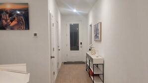 A hallway with a white door at the end, a white sink, and a shelf with a vase. - Sequoia Deluxe / Brand New 5 beds/ 3.5 baths  (Visalia)