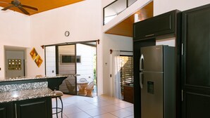 Una cuina moderna amb un refrigerador gran, armaris foscos i un paviment de rajola.