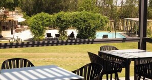 An outdoor seating area with tables and chairs, a pool, and greenery. - Finca del Sacramento (Colonia del Sacramento)