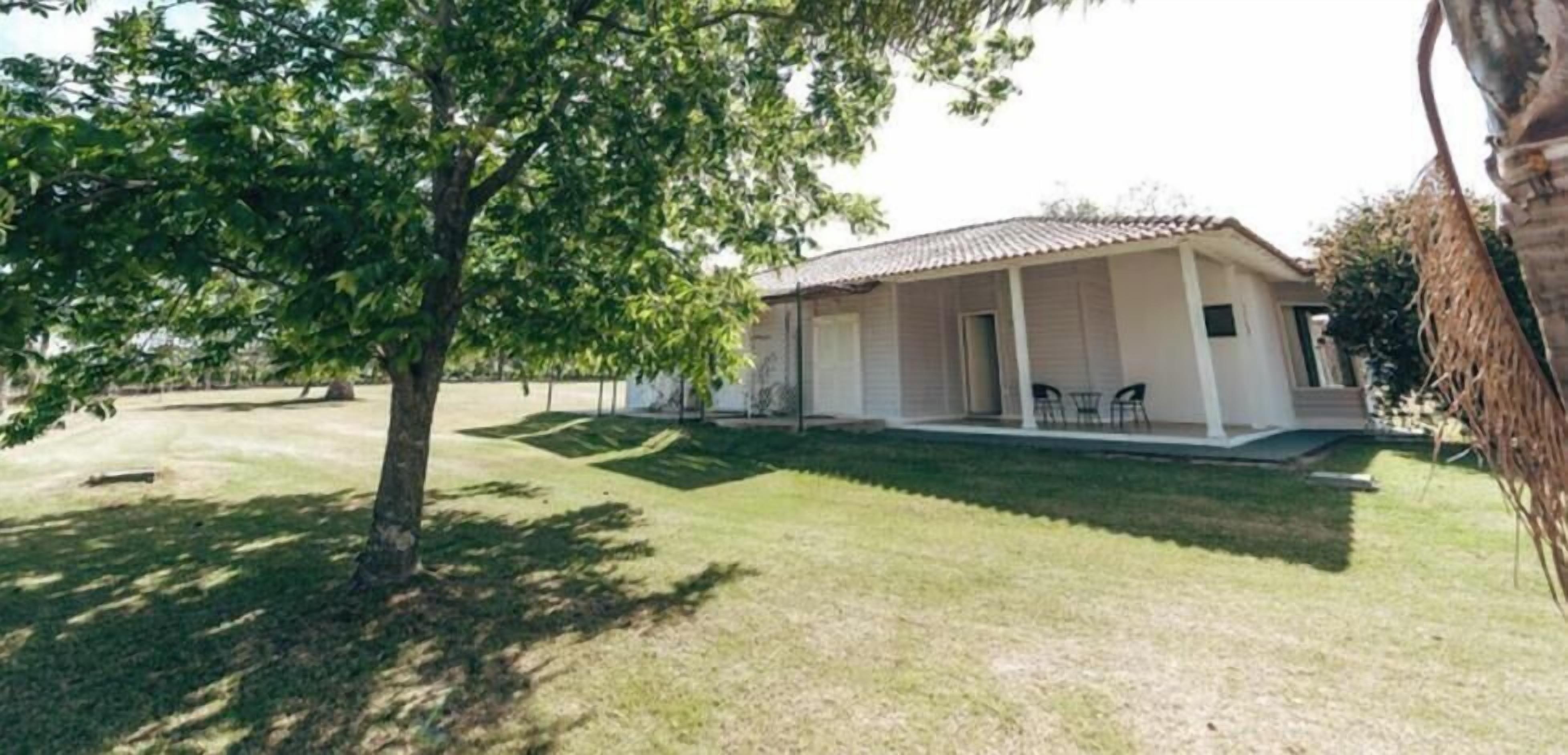 Een laag gebouw met een overdekte veranda, gazon en boom.