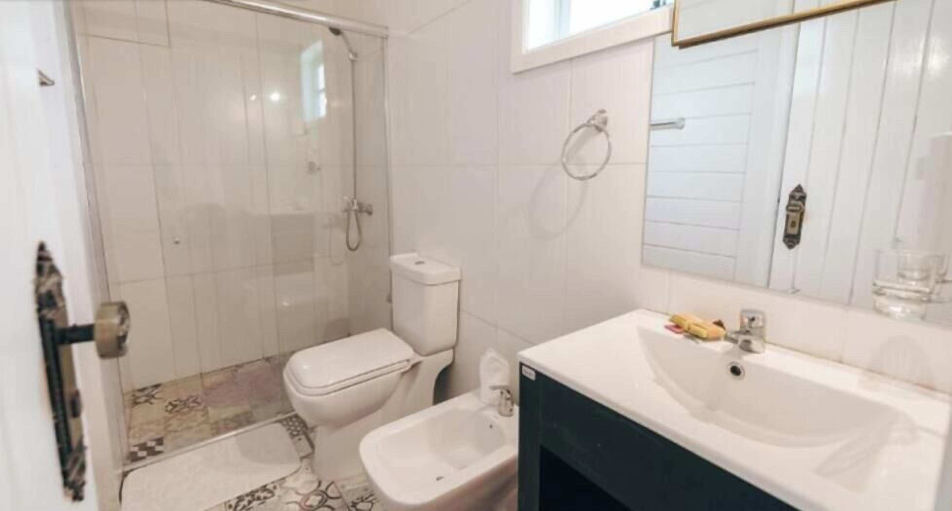 Un baño con ducha, inodoro, bidé, lavamanos y espejo.