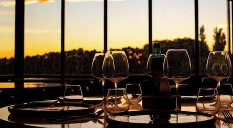 A table set for dining with wine glasses and a bottle, overlooking a scenic view.. Finca del Sacramento