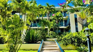 Ein mehrstöckiges Hotel mit einer zentralen Treppe, umgeben von üppiger Vegetation und tropischen Pflanzen.