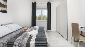 Moderni hotellihuone, jossa on sänky, työpöytä ja tuoli.