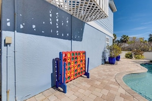 Un espace aménagé au bord de la piscine, avec un mur bleu, une piscine et un jeu de société aux couleurs vives.