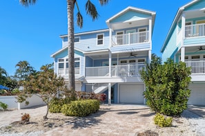 Ein Strandhaus mit zwei Etagen, einer überdachten Terrasse, einem Pool und einer Garage.