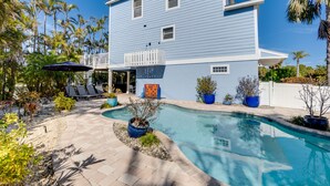 Une maison à deux étages dotée d’une piscine, d’un espace salon extérieur et d’un aménagement paysager de style tropical.