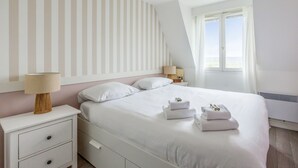 Un dormitorio ordenado con cama, mesitas de noche y ventana con cortinas.