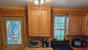 Une cuisine en bois avec une table à manger, des chaises, une cuisinière, un four à micro-ondes et une fenêtre donnant sur les arbres.