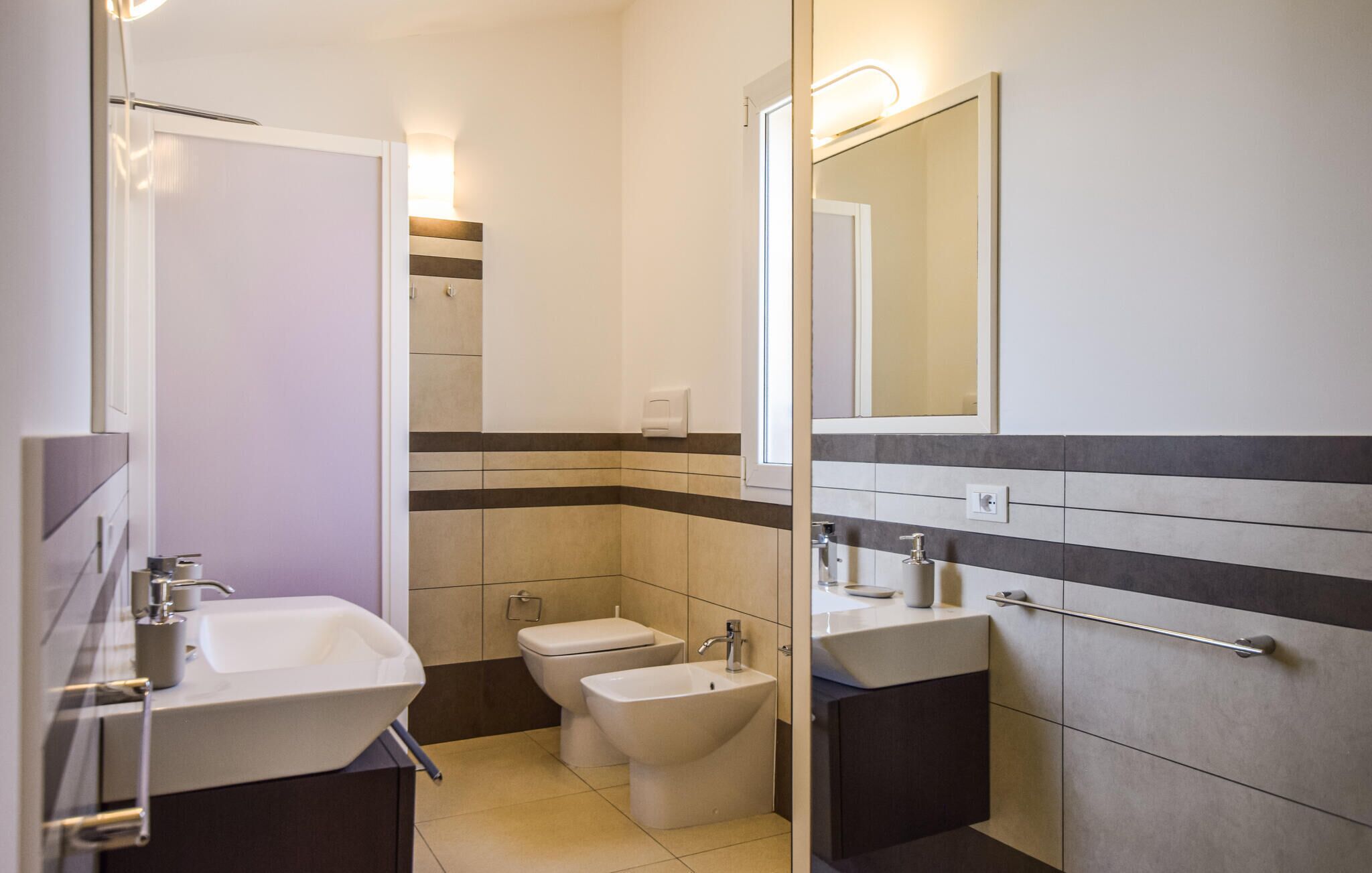 Ein modernes Badezimmer mit zwei Waschbecken, einem Bidet und einem Spiegel.