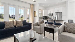 Una sala de estar moderna con un sofá azul oscuro, un sillón gris y una mesa de centro.