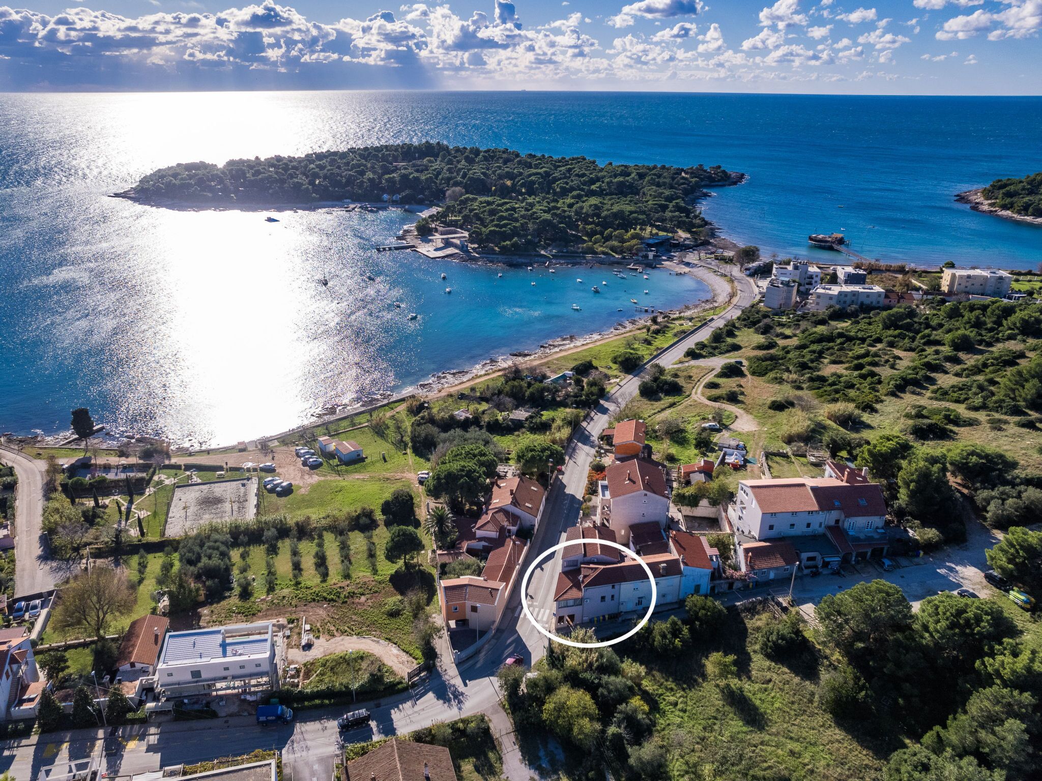 An aerial view of a coastal town with a marina, residential buildings, and a small island.