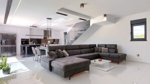 Ein modernes Wohnzimmer mit einer Eckcouch, einem Couchtisch und einer Küche im Hintergrund.