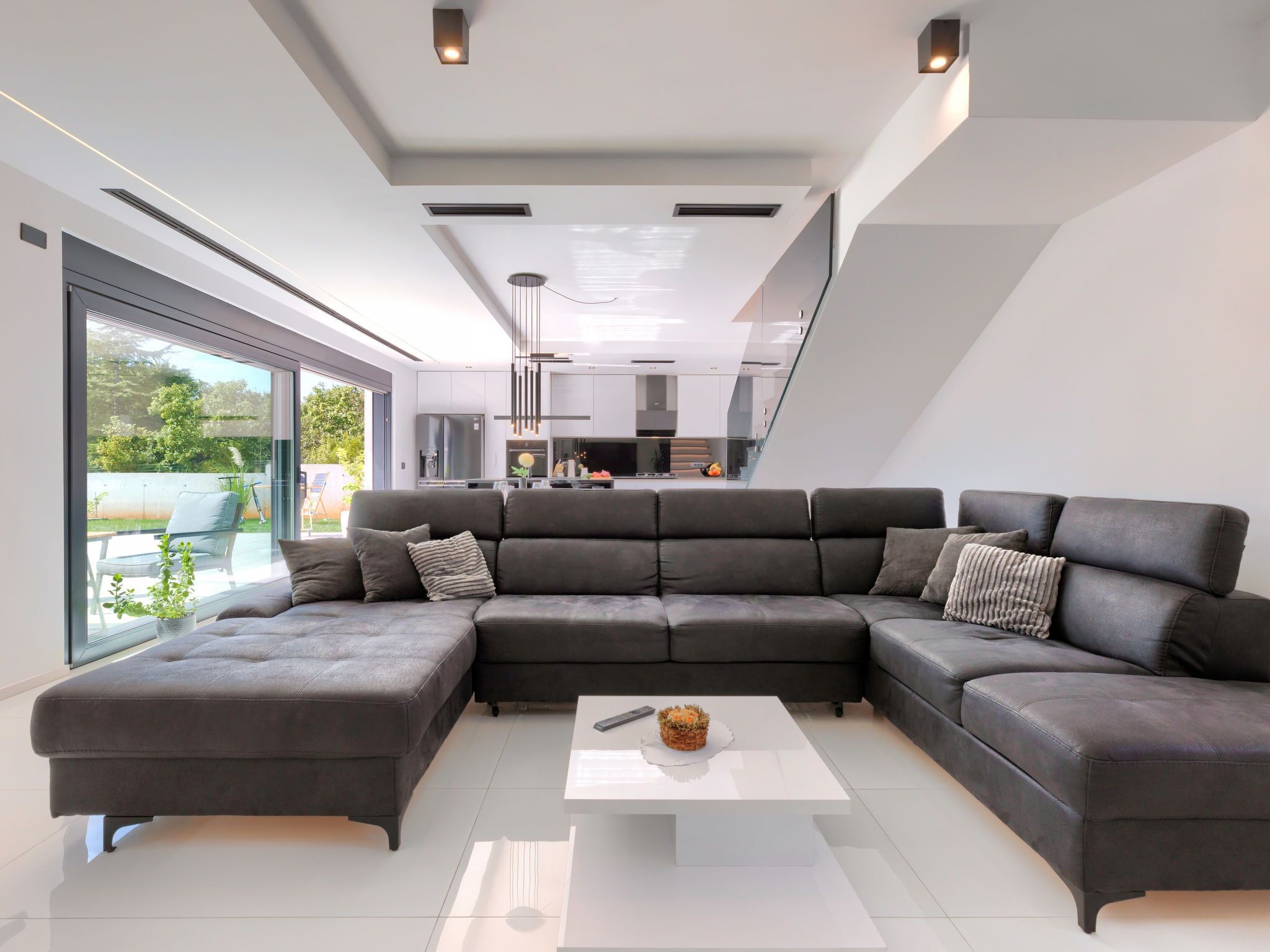 Una sala de estar moderna con un sofá modular, una mesa de centro y vistas a la cocina y al área exterior.