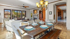 Un comedor amplio con una mesa de madera dispuesta para seis personas, un candelabro y una chimenea.