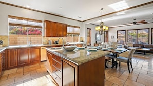 Una cocina amplia con armarios de madera, una isla grande y una zona de comedor con sofá y mesa.