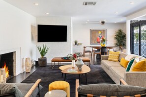 Una sala de estar moderna con chimenea, comedor y sofá con cojines.
